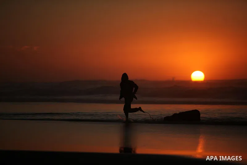 A Palestinian man walks on the beach of Gaza City, during the last sunset of 2016, on December 31, 2016. Photo by Ashraf Amra