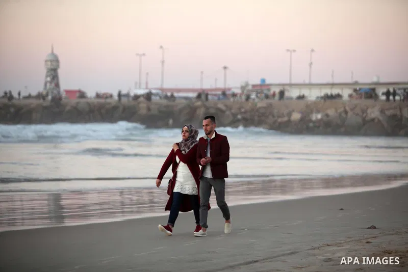 Palestinians walk on the beach of Gaza City, during the last sunset of 2016, on December 31, 2016. Photo by Ashraf Amra
