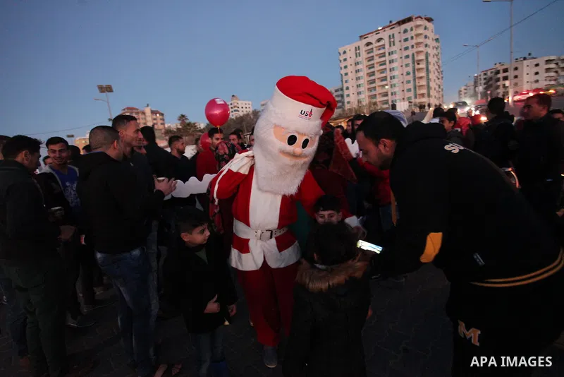 A Palestinian man in Santa Claus costume takes part in the celebration of the New Year at the Gaza seaport, on December 31, 2016. Photo by Ashraf Amra