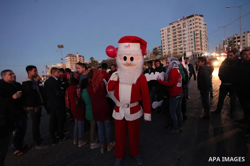A Palestinian man in Santa Claus costume takes part in the celebration of the New Year at the Gaza seaport, on December 31, 2016. Photo by Ashraf Amra