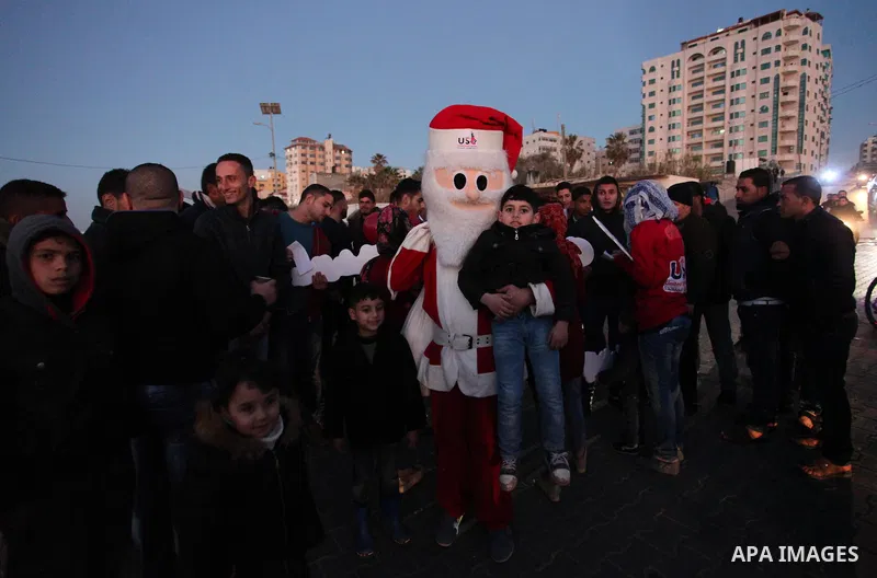 A Palestinian man in Santa Claus costume takes part in the celebration of the New Year at the Gaza seaport, on December 31, 2016. Photo by Ashraf Amra