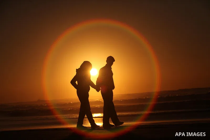 Palestinians walk on the beach of Gaza City, during the last sunset of 2016, on December 31, 2016. Photo by Ashraf Amra