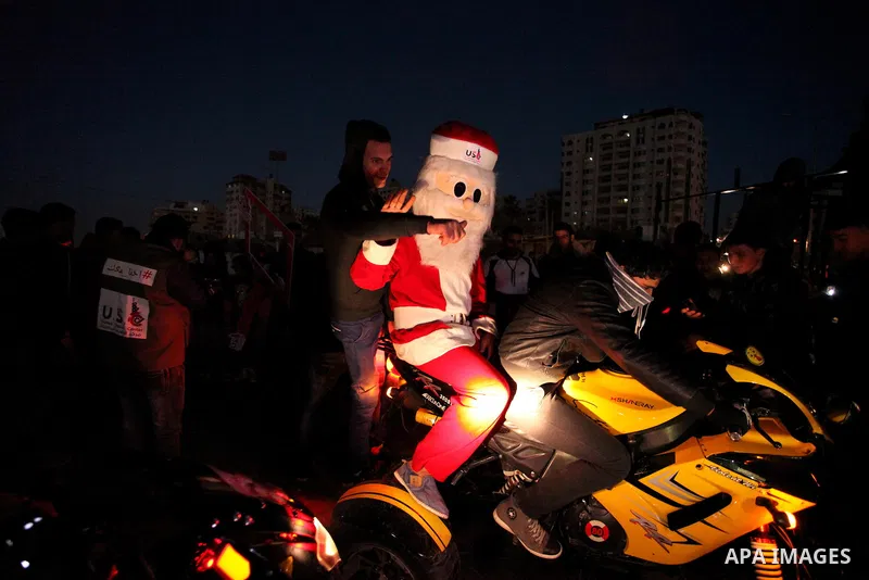 A Palestinian man in Santa Claus costume takes part in the celebration of the New Year at the Gaza seaport, on December 31, 2016. Photo by Ashraf Amra