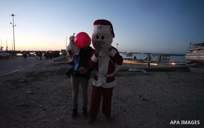 A Palestinian man in Santa Claus costume takes part in the celebration of the New Year at the Gaza seaport, on December 31, 2016. Photo by Ashraf Amra
