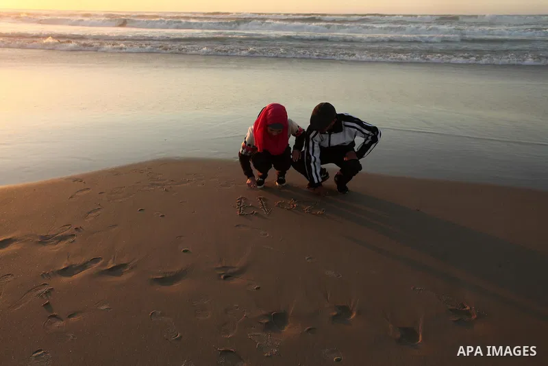 Palestinians write on a sand read "2017" during the last sunset of 2016 on the beach of Gaza City, on December 31, 2016. Photo by Ashraf Amra