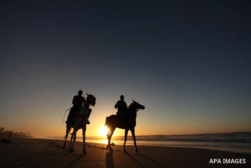 Palestinian men ride their horse as they enjoy the last sunset of 2016 at the beach of Gaza city, on the December 31, 2016. Photo by Ashraf Amra