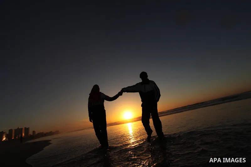Palestinians walk on the beach of Gaza City, during the last sunset of 2016, on December 31, 2016. Photo by Ashraf Amra