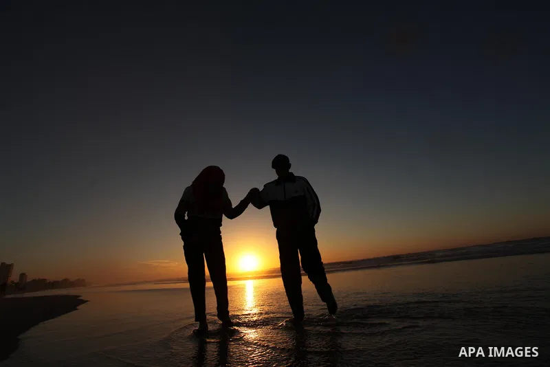 Palestinians walk on the beach of Gaza City, during the last sunset of 2016, on December 31, 2016. Photo by Ashraf Amra