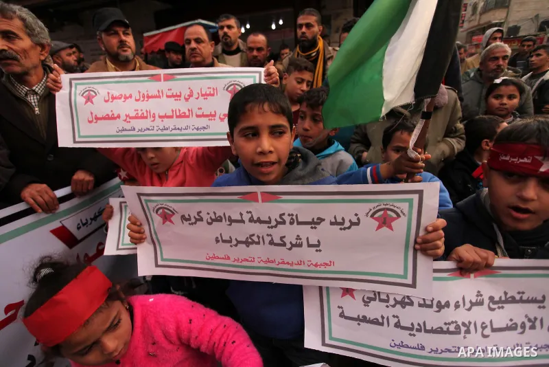 Palestinian children hold placards and light candles during a protest against a power cut in Bureij refugee camp, central Gaza Strip, on January 3, 2017. Photo by Ashraf Amra
