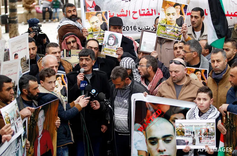 Palestinians hold photos of their relatives who were allegedly involved in attacks and consequently killed by Israeli forces, during a protest to demand the return of their bodies in the West Bank city of Hebron on Janua...