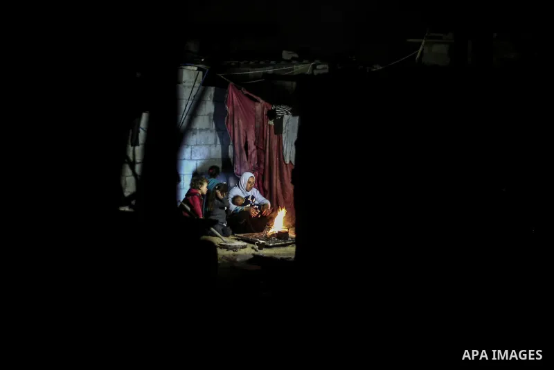 A picture taken on January 5, 2017 shows Palestinian family warm themselves around the fire inside their dwellings during the power cut on winter season in Khan Younis, in the southern Gaza strip. Photo by Mohammed Dahma...
