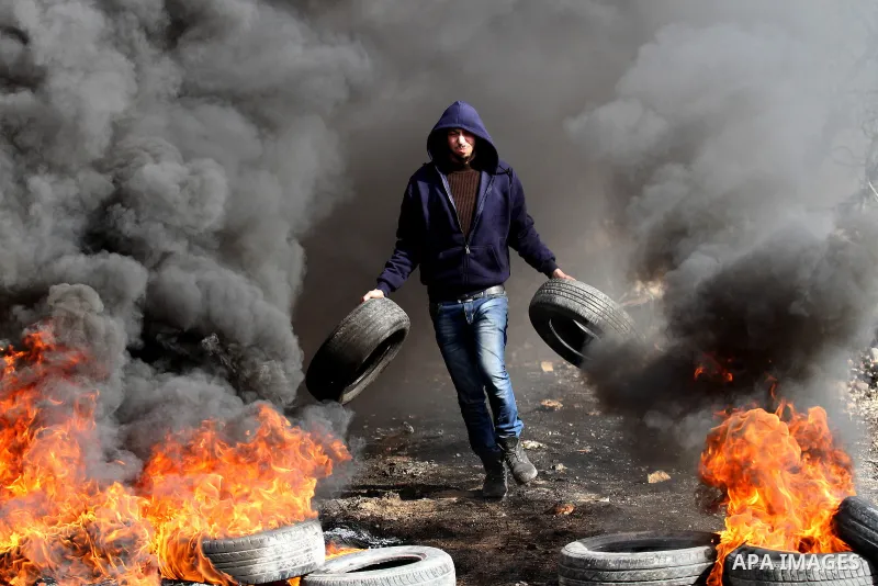 A Palestinian protester carries tires during clashes with Israeli security forces following a demonstration against the expropriation of Palestinian land by Israel in the village of Kfar Qaddum, near Nablus, in the occup...