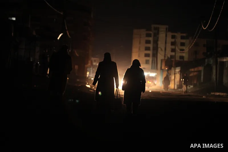 Palestinians walk on a road during a power cut in Shati refugee camp on 14 January 2017. Photo by Ashraf Amra