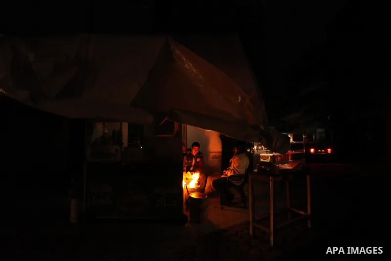 Palestinian family warm themselves around the fire outside their dwellings during the power cut on winter season in Shati refugee camp on 14 January 2017. Photo by Ashraf Amra