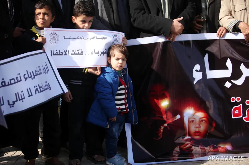 Palestinians hold placards during a demonstration against the ongoing electricity shortages in Gaza city on January 15, 2017. Power shortages in the Palestinian enclave have occurred repeatedly in recent weeks, with home...