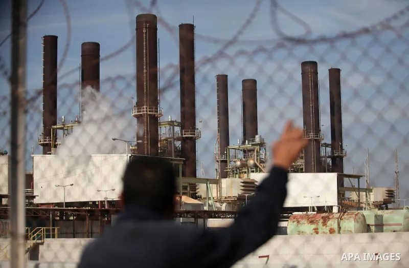 A Palestinian man looks to Gaza's power plant through a barbed fence in Nuseirat in the central Gaza Strip January 16, 2017. Photo by Ashraf Amra