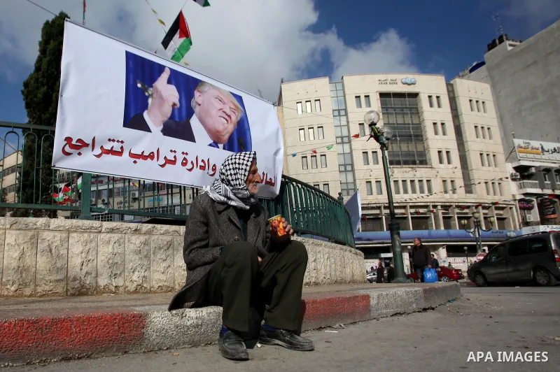 A Palestinian man sits under a banner against a promise by U.S. President-elect Donald Trump to relocate the U.S. embassy to Jerusalem, in the West Bank city of Nablus January 19, 2017. Photo by Nedal Eshtayah