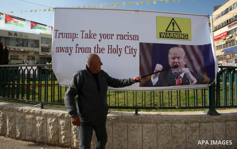 A Palestinian man walks past a banner against a promise by U.S. President-elect Donald Trump to relocate the U.S. embassy to Jerusalem, in the West Bank city of Nablus January 19, 2017. Photo by Nedal Eshtayah