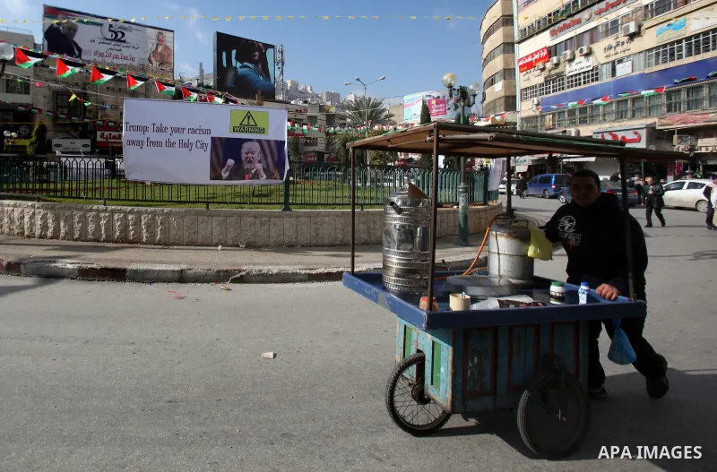 A Palestinian vendor passes by a banner against a promise by U.S. President-elect Donald Trump to relocate the U.S. embassy to Jerusalem, in the West Bank city of Nablus January 19, 2017. Photo by Nedal Eshtayah