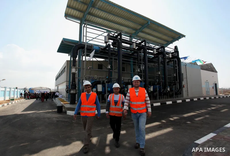 Palestinian workers walk outside the Seawater Desalination Plant-Southern Gaza during the inauguration ceremony which completed with generous support from the European union Implemented by UNICEF in partnership with Pale...