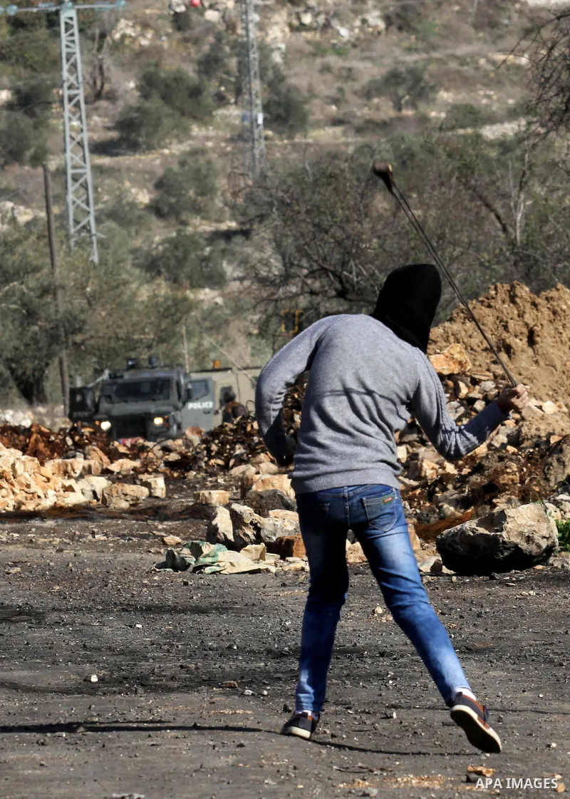 A Palestinian protester uses a slingshot to hurl stones towards Israeli security forces during clashes following a demonstration against the expropriation of Palestinian land by Israel in the village of Kfar Qaddum, near...