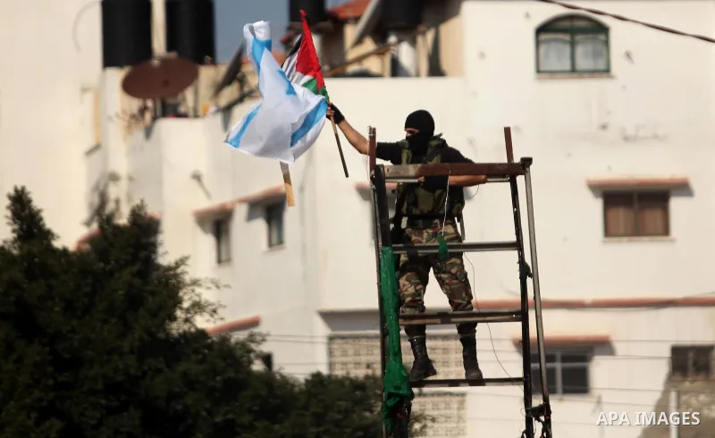 A member of Palestinian National Security Forces loyal to Hamas hangs a Palestinian flag after removing an Israeli flag from a mock Israeli army post as part of a drill during a graduation ceremony, in Gaza City January...