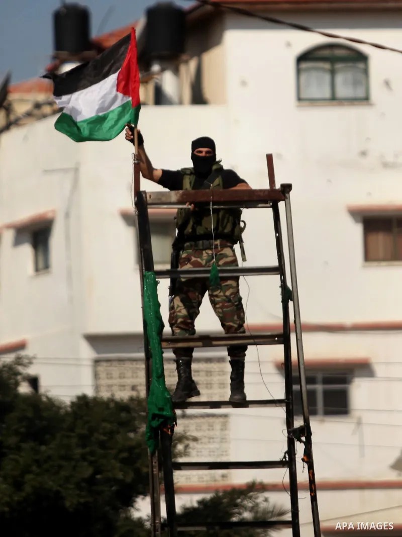 A member of Palestinian National Security Forces loyal to Hamas hangs a Palestinian flag after removing an Israeli flag from a mock Israeli army post as part of a drill during a graduation ceremony, in Gaza City January...