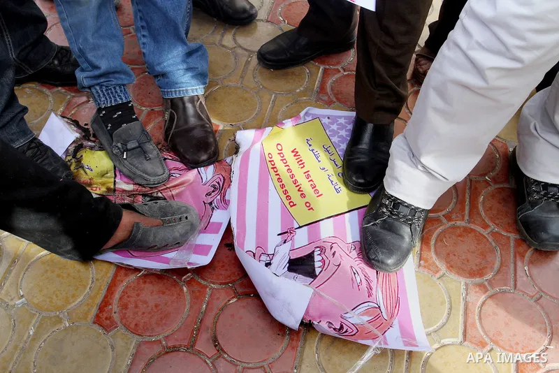 Palestinian protestors step on a placard depicting US President Donald Trump during a demonstration against his pledge to move his country's embassy to Jerusalem, in Rafah in the southern Gaza Strip on January 24, 2017....