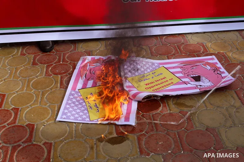 Palestinian protestors burn a placard depicting US President Donald Trump during a demonstration against his pledge to move his country's embassy to Jerusalem, in Rafah in the southern Gaza Strip on January 24, 2017. Tru...