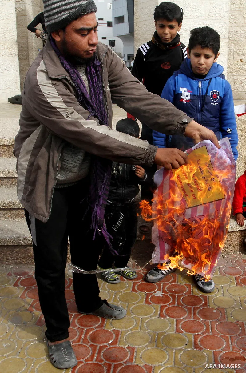 Palestinian protestors burn a placard depicting US President Donald Trump during a demonstration against his pledge to move his country's embassy to Jerusalem, in Rafah in the southern Gaza Strip on January 24, 2017. Tru...