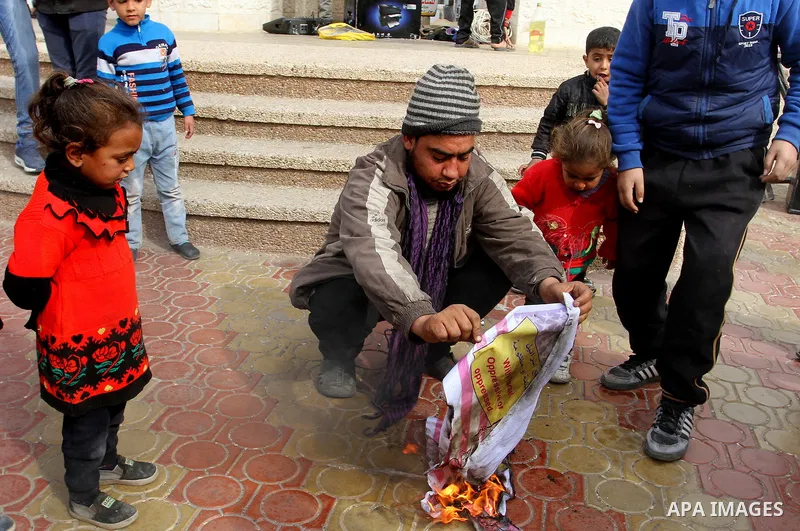 Palestinian protestors burn a placard depicting US President Donald Trump during a demonstration against his pledge to move his country's embassy to Jerusalem, in Rafah in the southern Gaza Strip on January 24, 2017. Tru...