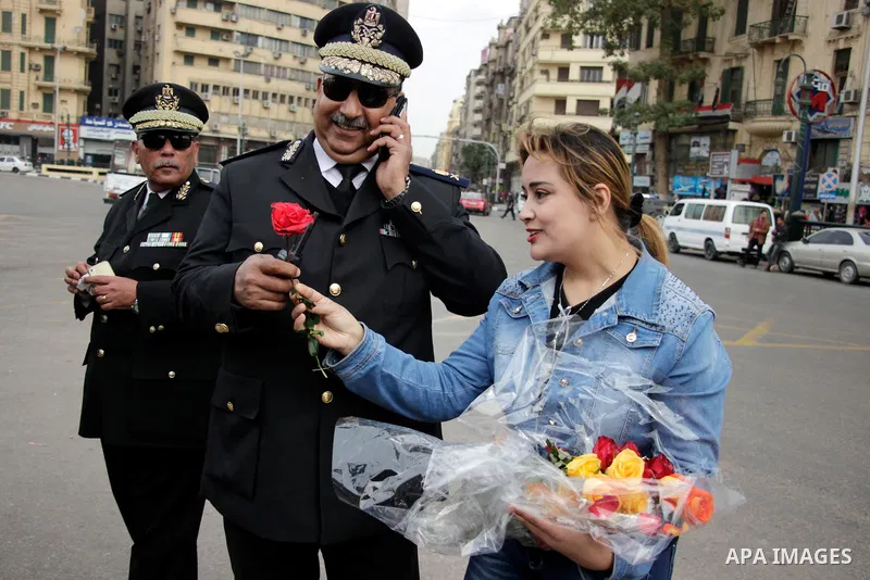 A supporter of Egypt's President Abdel Fattah al-Sisi distributes flowers to policemen marking Police Day, which falls on Jan. 25, and is also the anniversary of the 2011 uprising, in Tahrir Square, Cairo, Egypt, on Janu...