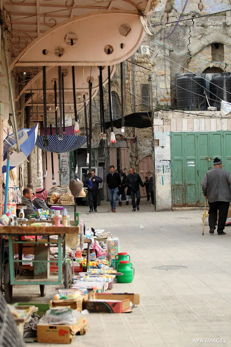 Palestinians walk at a market in the Old City of the West Bank town of Hebron, on January 25, 2017. Photo by Wisam Hashlamoun