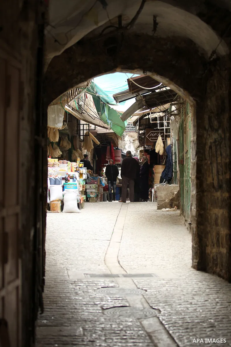 Palestinians walk at a market in the Old City of the West Bank town of Hebron, on January 25, 2017. Photo by Wisam Hashlamoun