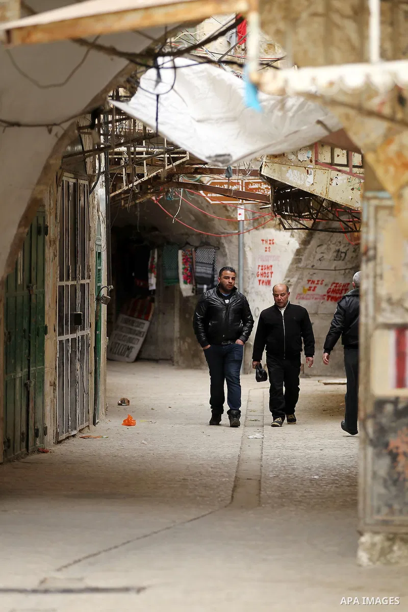 Palestinians walk at a street in the Old City of the West Bank town of Hebron, on January 25, 2017. Photo by Wisam Hashlamoun
