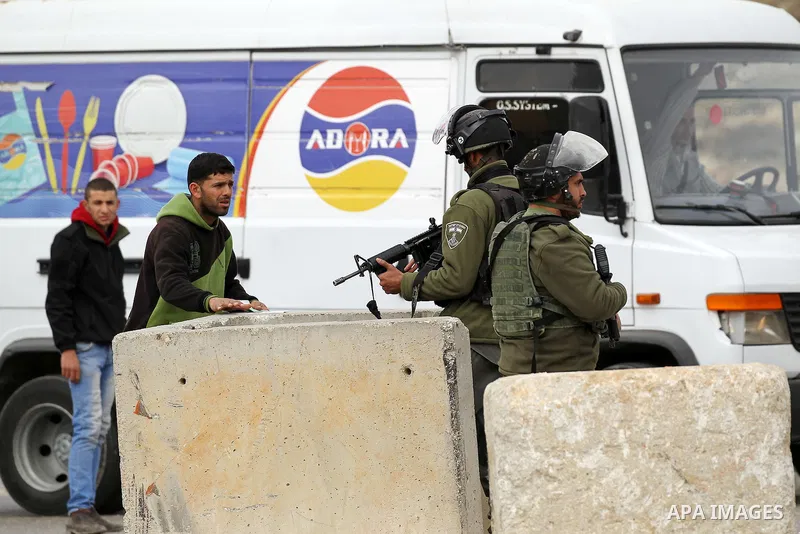 Israeli soldiers check the identity cards of Palestinians at a checkpoint in the West Bank village of Bani Na'im, near Hebron, on January 26, 2017. Photo by Wisam Hashlamoun