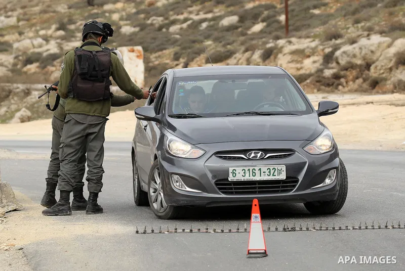 Israeli soldiers check the identity cards of Palestinians at a checkpoint in the West Bank village of Bani Na'im, near Hebron, on January 26, 2017. Photo by Wisam Hashlamoun