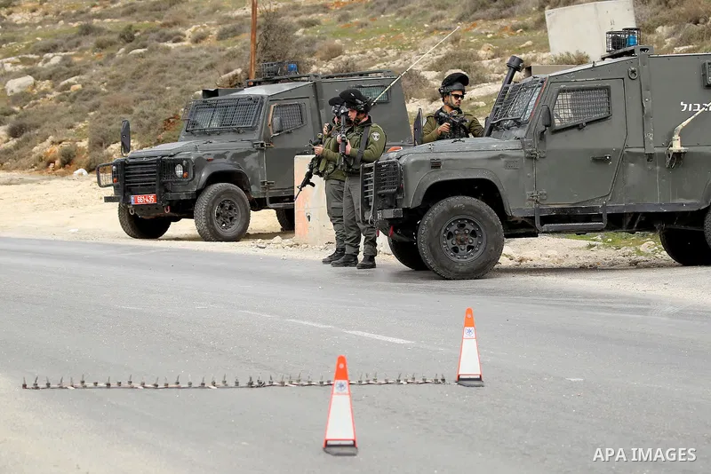 Israeli soldiers stand guard at a checkpoint in the West Bank village of Bani Na'im, near Hebron, on January 26, 2017. Photo by Wisam Hashlamoun