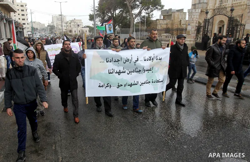 Palestinian protestors hold a banner reading in Arabic: "We want our children in the land of our ancestors, return the bodies of our martyrs, it is right and dignity" during a demonstration demanding that Israeli authori...