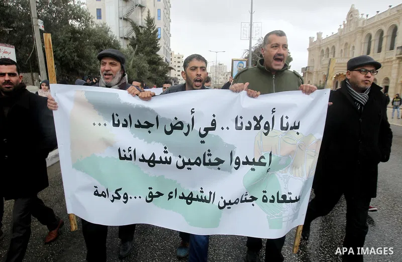 Palestinian protestors hold a banner reading in Arabic: "We want our children in the land of our ancestors, return the bodies of our martyrs, it is right and dignity" during a demonstration demanding that Israeli authori...
