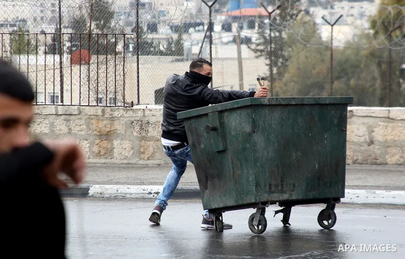 A Palestinian protestor uses a slingshot to throw stones towards Israeli security forces during clashes following a demonstration demanding that Israeli authorities return the bodies of Palestinians killed during attacks...