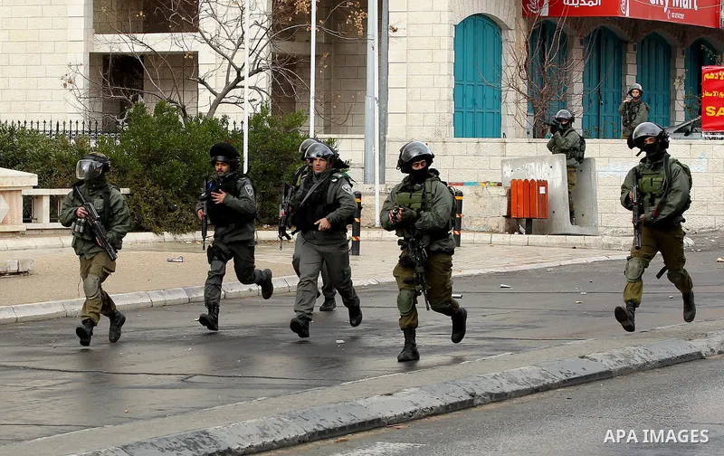 Israeli security forces run during clashes with Palestinian protesters following a demonstration demanding that Israeli authorities return the bodies of Palestinians killed during attacks on Israel, in the West Bank town...