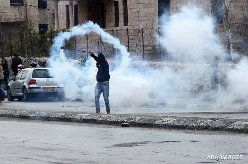 A Palestinian protestor uses a slingshot to throws back a tear gas canister towards Israeli security forces during clashes following a demonstration demanding that Israeli authorities return the bodies of Palestinians ki...