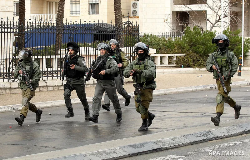 Israeli security forces run during clashes with Palestinian protesters following a demonstration demanding that Israeli authorities return the bodies of Palestinians killed during attacks on Israel, in the West Bank town...