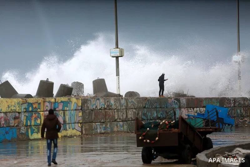 A Palestinian man stands on wall as a huge wave crash over a sea wall at the Gaza seaport during a rainy and heavy wind weather prevails on the Mediterranean Sea, in Gaza City on January 28, 2017. Photo by Mohammed Asad