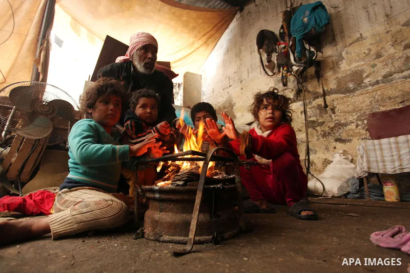 Palestinian children warm up in front of a fire in a hovel during the cold and rainy weather in the Jabalia refugee camp in the northern Gaza Strip on January 28, 2017. Photo by Ashraf Amra
