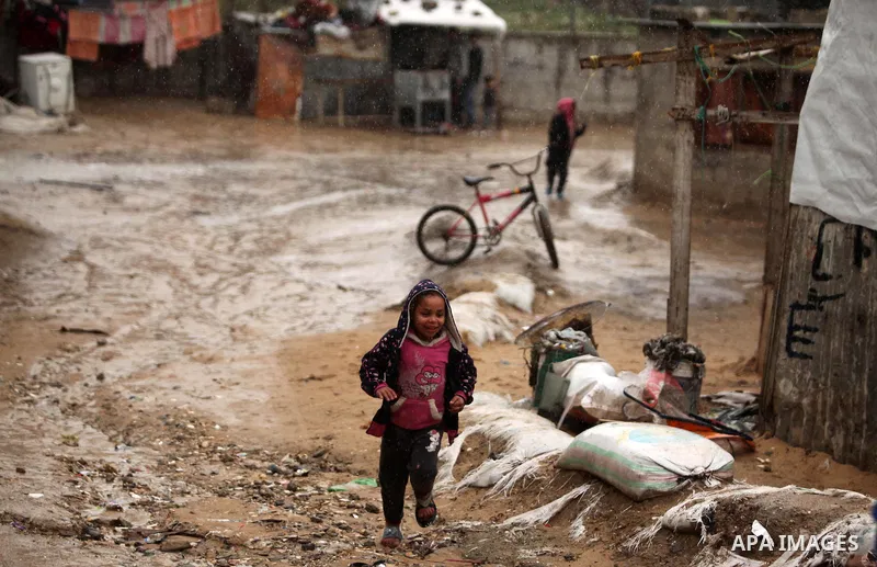 A Palestinian girl plays on a wet street during the cold and rainy weather in the Jabalia refugee camp in the northern Gaza Strip on January 28, 2017. Photo by Ashraf Amra