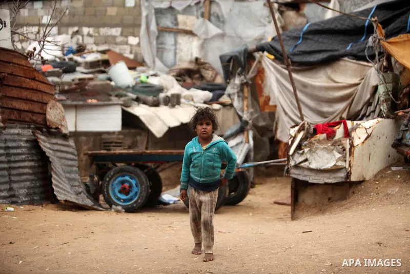 A Palestinian girl plays outside a hovel during the cold and rainy weather in the Jabalia refugee camp in the northern Gaza Strip on January 28, 2017. Photo by Ashraf Amra
