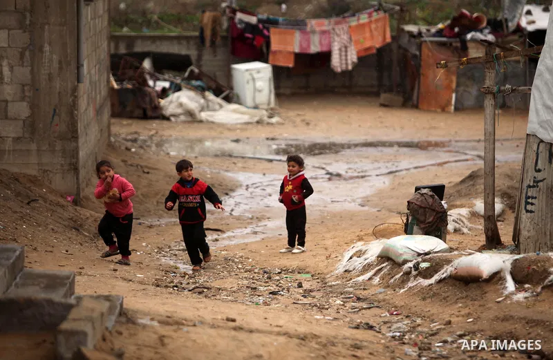 Palestinian children play outside a hovel during the cold and rainy weather in the Jabalia refugee camp in the northern Gaza Strip on January 28, 2017. Photo by Ashraf Amra