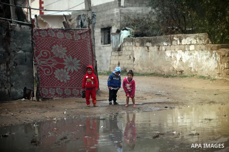 Palestinian children play outside a hovel during the cold and rainy weather in the town of Beit Lahia in the northern Gaza Strip on January 28, 2017. Photo by Ashraf Amra